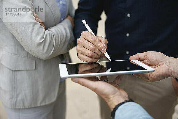 Hand eines Geschäftsmannes  der auf einem Tablet-PC steht und Kollegen unterschreibt