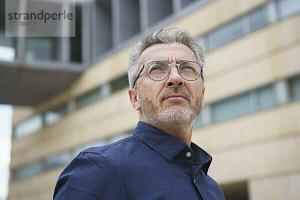 Geschäftsmann mit Brille vor Bürogebäude