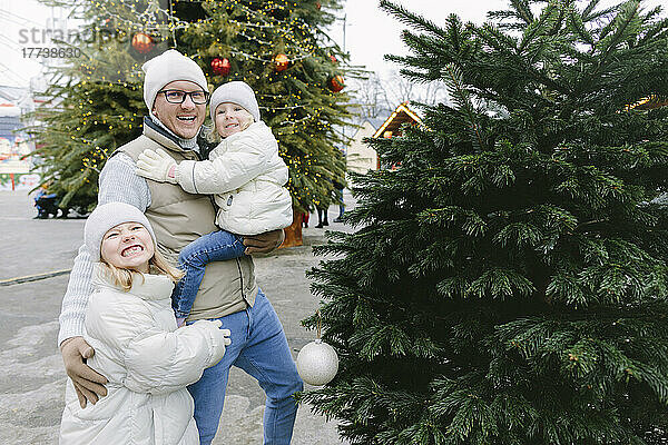 Glücklicher Vater mit Töchtern am Weihnachtsbaum