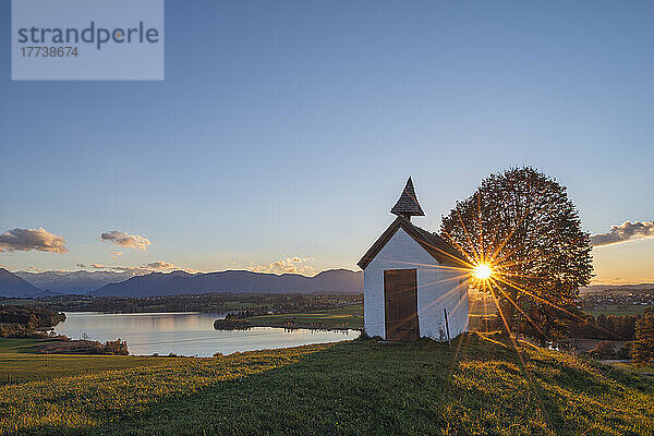 Germany  Bavaria  Aidling  Mesnerhauskapelle at sunset with Riegsee lake in background