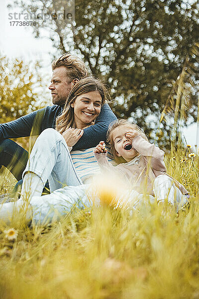 Smiling mother and father with daughter in meadow