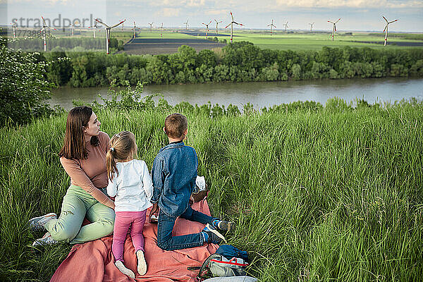 Mutter mit Tochter und Sohn schauen sich am Wochenende Windkraftanlagen im Feld an