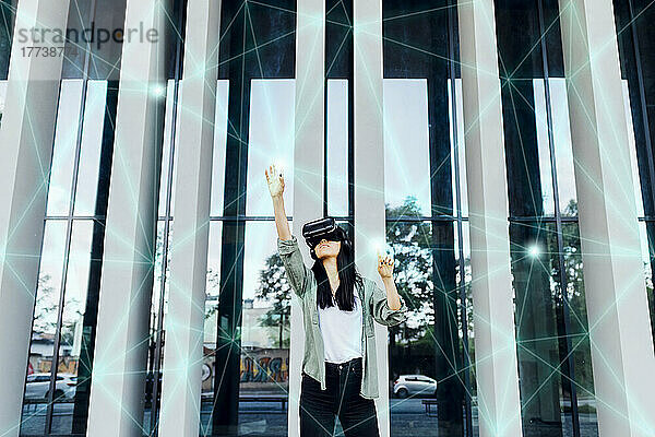 Frau trägt VR-Simulator mit erhobener Hand über transparente Schnittstelle
