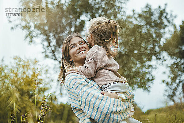 Happy mother embracing daughter in meadow
