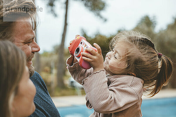 Mädchen fotografiert Vater und Mutter mit Spielzeugkamera