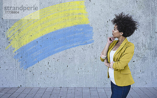Young woman looking at painted Ukrainian flag on wall