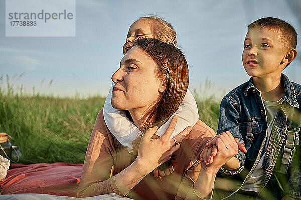 Lächelnde Mutter und Kinder zusammen im Feld beim Picknick