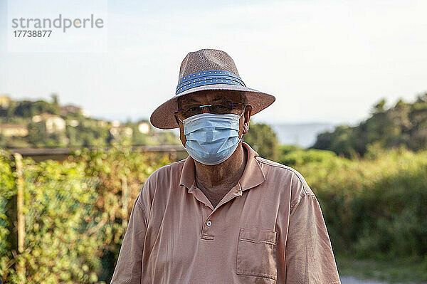 Älterer Tourist mit Hut und schützender Gesichtsmaske