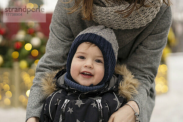 Netter Junge mit Mutter auf dem Weihnachtsmarkt