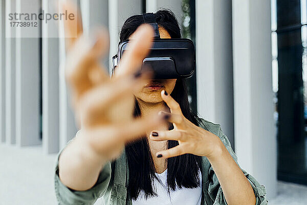 Frau mit Virtual-Reality-Simulator gestikuliert mit den Händen