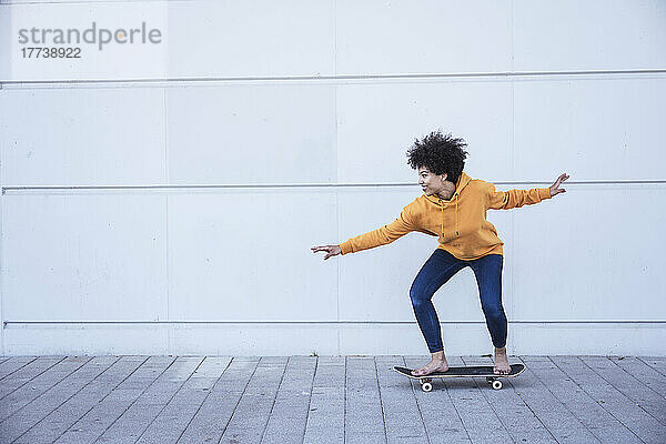 Frau fährt Skateboard vor der Wand