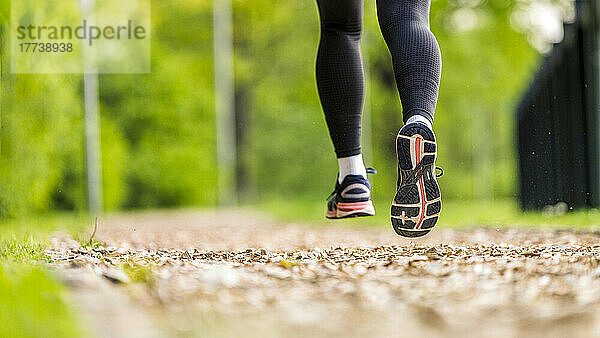 Junge Frau trägt Sportschuhe beim Joggen im Park