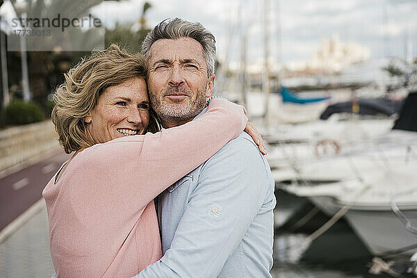 Glückliche reife Frau umarmt Mann am Hafen