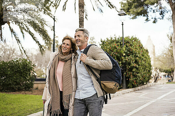 Älteres Paar mit Rucksack spaziert im Urlaub im Park