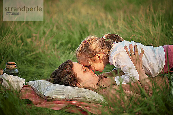 Mutter und Tochter reiben sich beim Picknick im Gras die Nase