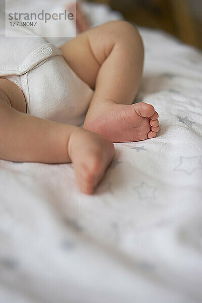 Legs of baby boy on bed at home