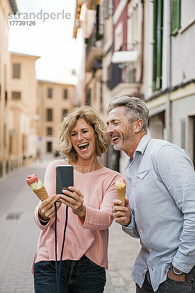 Fröhliches reifes Paar mit Eis  das in der Stadt ein Selfie mit dem Smartphone macht