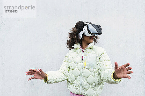 Girl wearing virtual reality headset gesturing in front of white wall