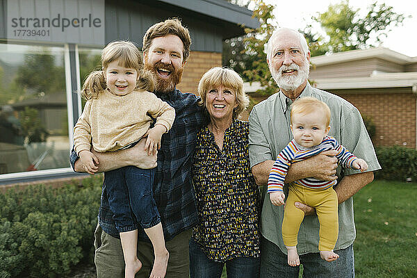 Porträt einer lächelnden Drei-Generationen-Familie mit Kindern (2-3  4-5) im Hinterhof