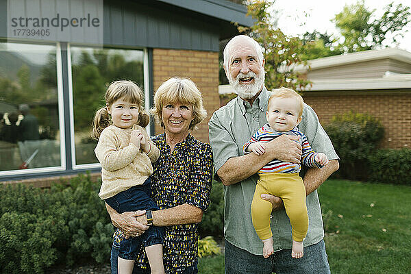Porträt lächelnder Großeltern mit Enkelkindern (2-3  4-5) im Hinterhof