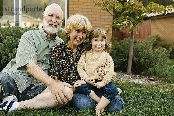 Porträt lächelnder Großeltern mit Enkelin (4-5) im Hinterhof