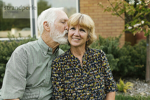 Älterer Mann küsst Frau im Hinterhof