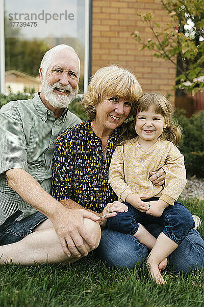 Porträt lächelnder Großeltern mit Enkelin (4-5) im Hinterhof