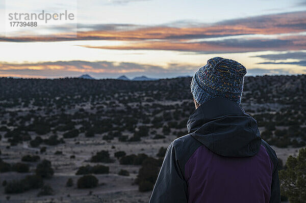 USA  New Mexico  Lamy  Rückansicht einer Frau in Wüstenlandschaft bei Sonnenuntergang im Galisteo Basin Preserve