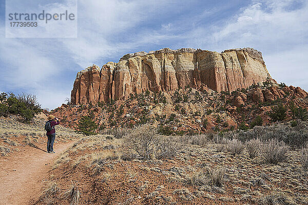 USA  New Mexico  Abiquiu  Rückansicht einer Wanderin  die Mesa in einer Wüstenlandschaft fotografiert