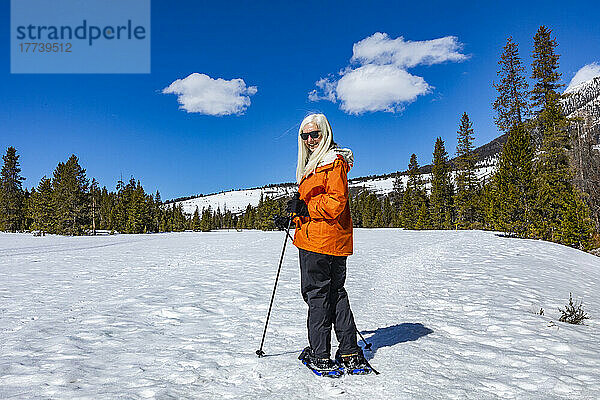 USA  Idaho  Ketchum  ältere blonde Frau beim Schneeschuhwandern in schneebedeckter Landschaft