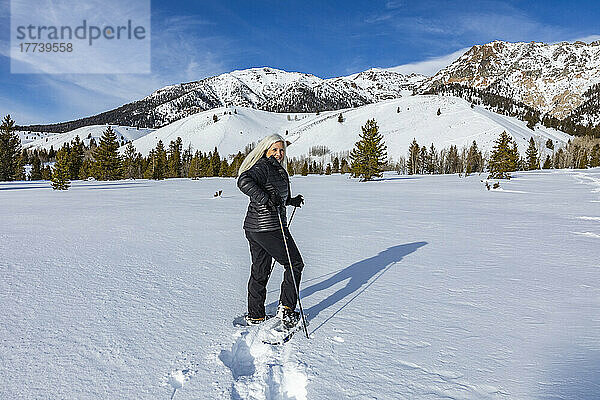USA  Idaho  Ketchum  ältere blonde Frau beim Schneeschuhwandern in schneebedeckter Landschaft