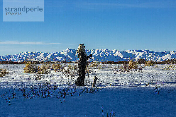 USA  Idaho  Bellevue  ältere blonde Frau beim Schneeschuhwandern in schneebedeckter Landschaft