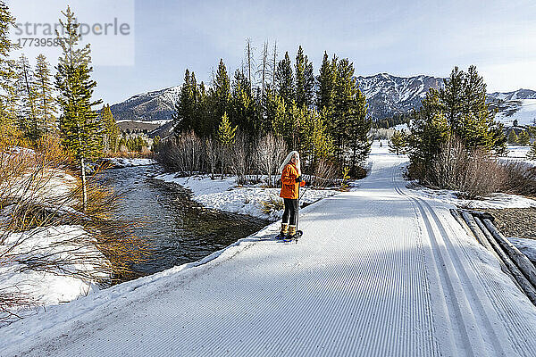 USA  Idaho  Ketchum  ältere blonde Frau beim Schneeschuhwandern in einer schneebedeckten Landschaft