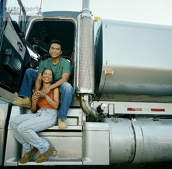 Paar sitzt vor der Tür eines Lastwagens