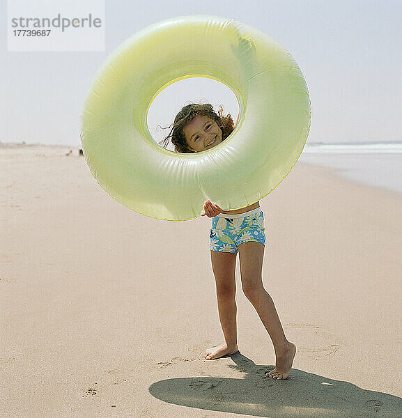 Mädchen (4-5) hält aufblasbaren Ring am Strand