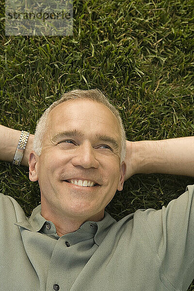 Reifer Mann liegt auf Gras und lächelt