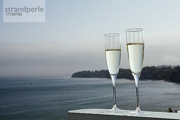 Zwei Gläser Champagner mit Meer im Hintergrund
