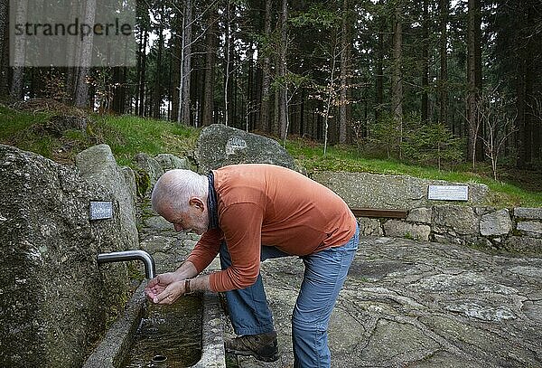 Wanderer erfrischt sich am Quellwasser Brunnen beim 1000 m Platz  Sternstein Rundweg  Bad Leonfelden  Mühlviertel  Oberösterreich  Österreich  Europa