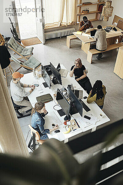 Blick von oben auf die Kollegen eines Startup-Unternehmens  die im Büro zusammenarbeiten
