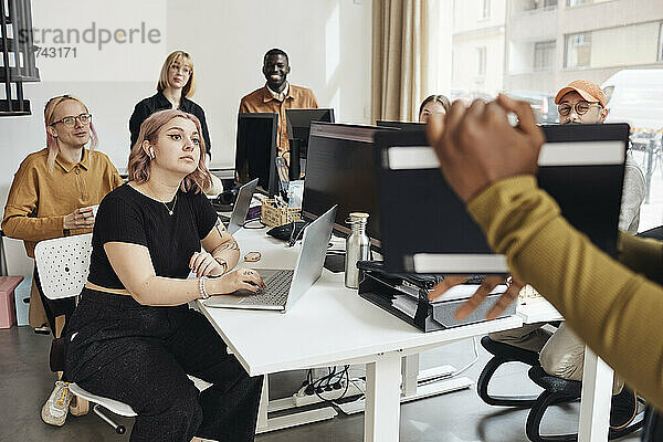 Startup-Kollegen sitzen am Schreibtisch und hören einer Geschäftsfrau zu  die bei einer Besprechung im Büro ihre Strategie erläutert