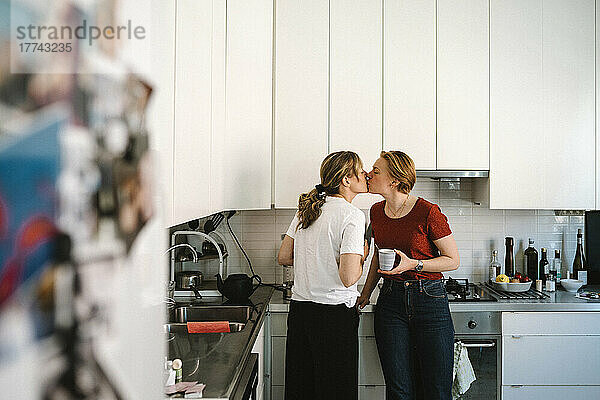 Zärtliches lesbisches Paar küsst sich in der Küche zu Hause