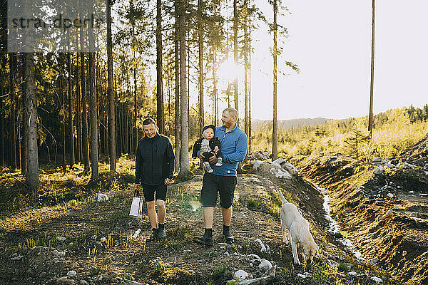 Eltern mit Sohn und Hund beim Spaziergang im Wald