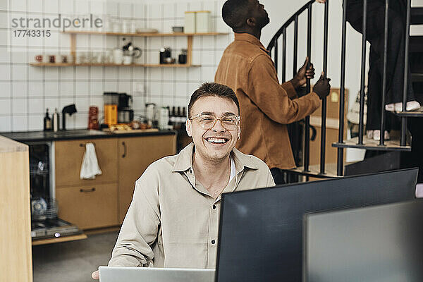 Porträt eines glücklichen männlichen Computerprogrammierers  der im Büro sitzt