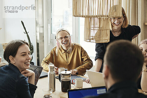 Glückliche multirassische Kollegen  die sich während einer Besprechung im Büro unterhalten
