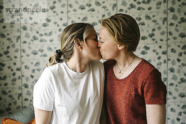 Romantisches lesbisches Paar  das sich zu Hause an der Wand küsst