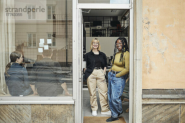 Weibliche Computerprogrammiererinnen stehen vor der Tür eines Büros eines Start-up-Unternehmens