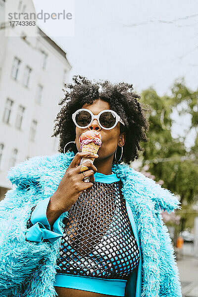 Junge Hipster-Frau mit Pelzjacke isst Eiscreme