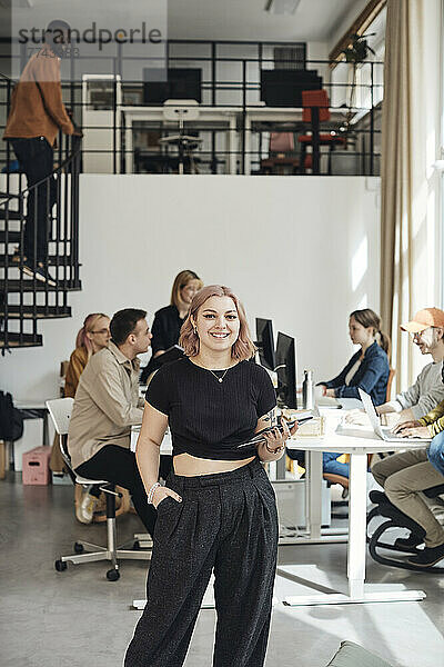 Porträt einer jungen Geschäftsfrau mit Hand in der Tasche  die in einem Büro eines Technologie-Start-ups steht
