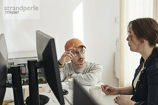 Männlicher Programmierer gestikuliert während einer Diskussion mit einer Kollegin im Büro eines Start-up-Unternehmens
