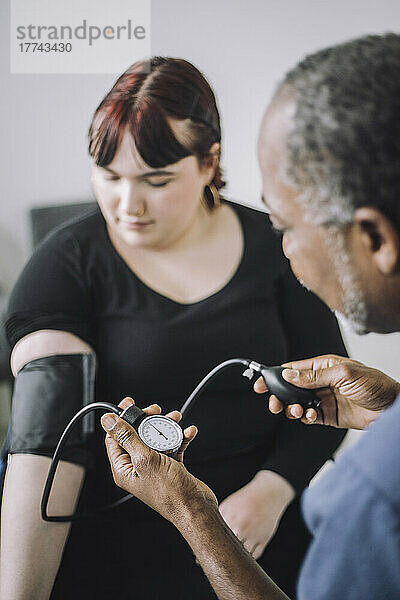 Männlicher Gesundheitsexperte untersucht den Blutdruck einer Patientin in einer medizinischen Klinik